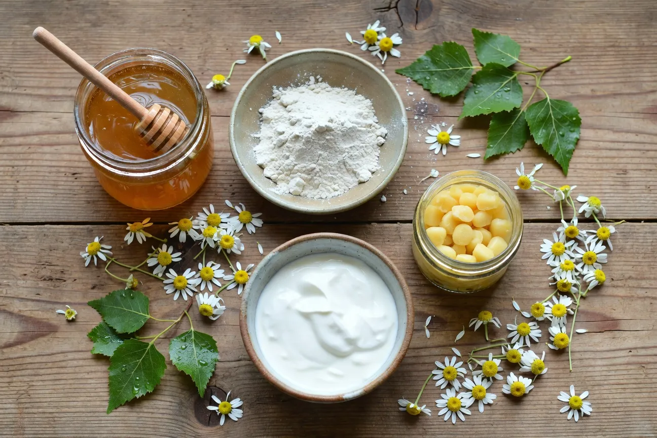 Cosmétiques naturels slaves disposés sur une table en bois : pot de miel, herbes séchées, argile blanche, bocaux de smetana et flacons d'huile de cèdre